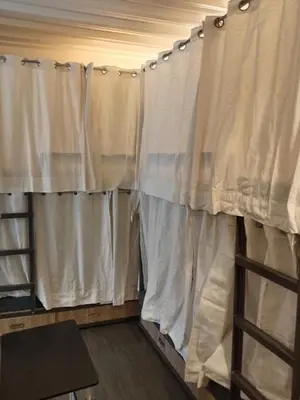a room with white curtains and a wooden table at Quarto Ph in Manila