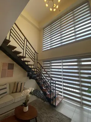 a living room with a spiral staircase and a couch at Edsa Heights Unit 3416 Cozy 1 br Loft Penthhouse Unit with 2 full beds Ama Tower in Manila