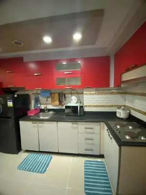 a kitchen with red cabinets and a black counter top at 2br Sea Residences pool view dina in Manila