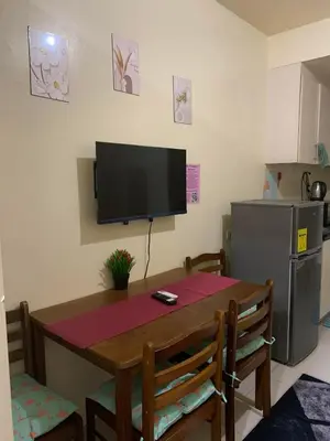 a kitchen with a table and a television on the wall at Sea Residences DINA in Manila