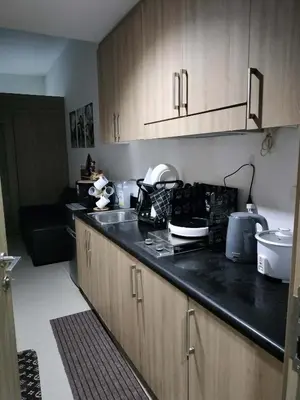 a kitchen with wooden cabinets and a black counter top at 17th floor Facing MOA in Manila