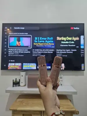 a person holding two remote controls in front of a tv at Wowstaycation in Manila