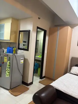 a kitchen with a bed and a refrigerator in a room at Newport Inn in Manila