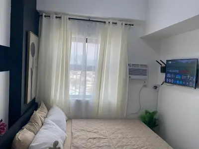 a bedroom with a bed in front of a window at The Courtyard Contemporary Studio at Taguig WiFi in Manila