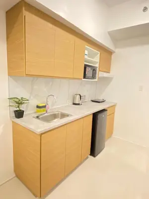 a kitchen with wooden cabinets and a sink at The Courtyard Contemporary Studio at Taguig WiFi in Manila
