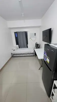 a small room with a bed and a desk in it at Ivy's CozyStaycation in Dasmariñas