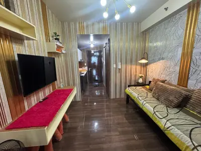 a living room with a couch and a flat screen tv at Air Residences MKT in Manila