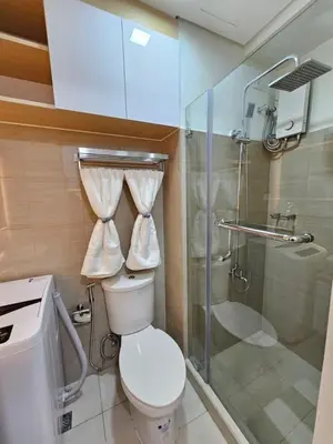 a bathroom with a toilet and a glass shower at Elegant MOA Condo at Shore Residence near the Bay in Manila