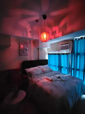a bedroom with a bed and a red light at Elivion Staycations in McKinley Hill BGC with Pool near Venice Mall in Manila