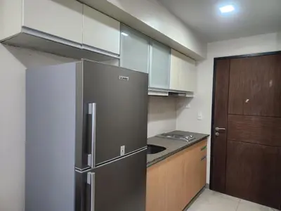 a kitchen with a stainless steel refrigerator and wooden cabinets at The Vibe BGC Uptown Apartment in Manila