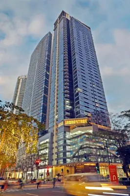 a tall building with many windows in a city at The Vibe BGC Uptown Apartment in Manila