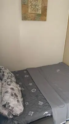 a bed with a comforter on it in a room at Cozy Apartment by Arah in Manila