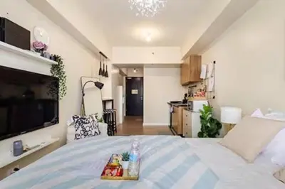 a bedroom with a bed with a tray of food on it at Studio Lune - Heart of Makati in Manila