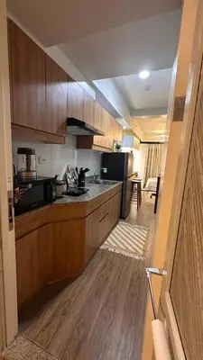 a kitchen with wooden cabinets and a black appliances at The Framehaus with Free Parking at Sonora Garden Residences, Las Pinas in Manila