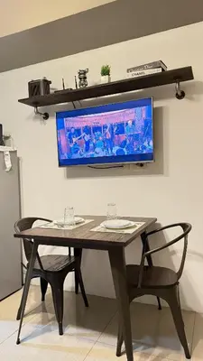 a table with two chairs and a television on a wall at The Luxe Nook Shore Residences MOA in Manila
