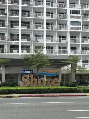 a large white building with a store sign in front of it at The Luxe Nook Shore Residences MOA in Manila