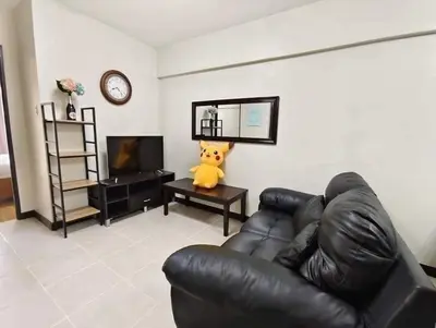a living room with a couch and a teddy bear on a table at Vacation in Tribecca Towers in Manila