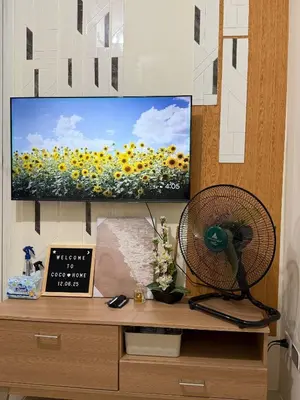 a flat screen tv sitting on top of a wooden cabinet at Coco Home in Manila