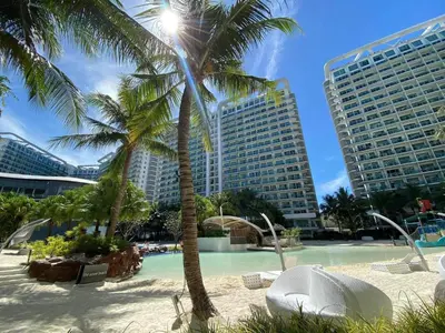 a resort with a pool and palm trees and buildings at Hotel Essence Service Road in Manila
