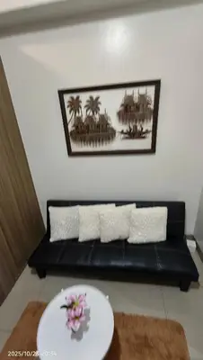 a black couch in a living room with a plate at Shore Residences Pasay in Manila