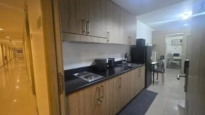 a kitchen with wooden cabinets and a black counter top at Book ME at Shore Residences Tower D near Airport & Mall of Asia in Manila