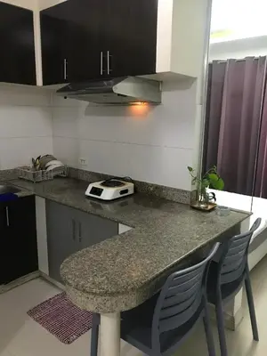 a kitchen with a counter with chairs and a table at Birch Tower Manila by JL in Manila