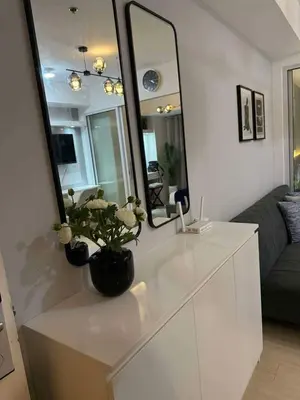 a mirror on top of a white dresser in a living room at Transient Home Serenity in Manila