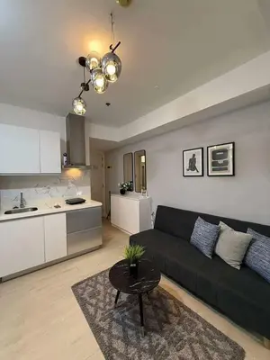 a living room with a black couch and a kitchen at Transient Home Serenity in Manila