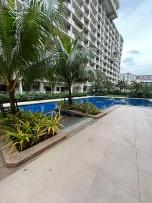 a swimming pool with palm trees and a building at Calathea Place - Bel's Cozy Staycation in Manila