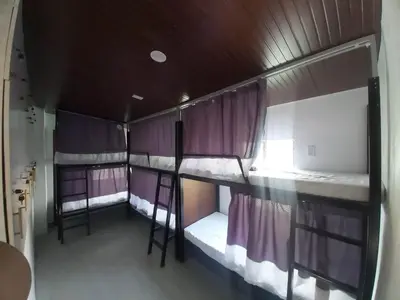 three bunk beds in a room with purple curtains at Fernica Boarding House in Carmona
