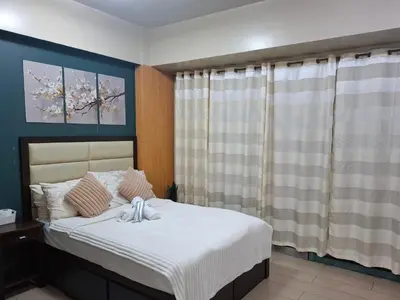 a bedroom with a bed with white sheets and a window at Palme d'Or Stay in Manila