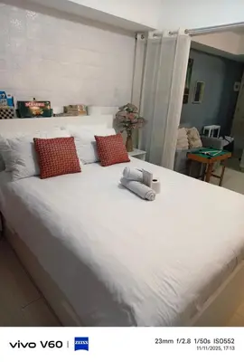 a white bed with red pillows and a teddy bear on it at The Infinity Staycation in Manila