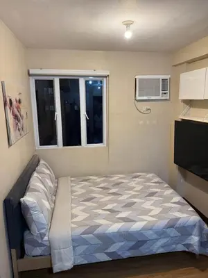 a small bedroom with a bed and a window at Studio Near NAIA Airport in Manila