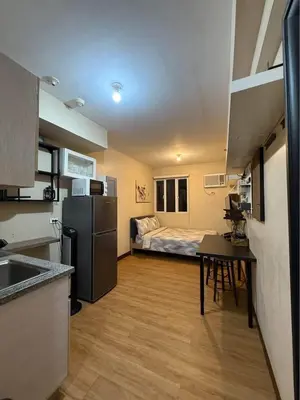 a kitchen with a refrigerator and a bed in a room at Studio Near NAIA Airport in Manila