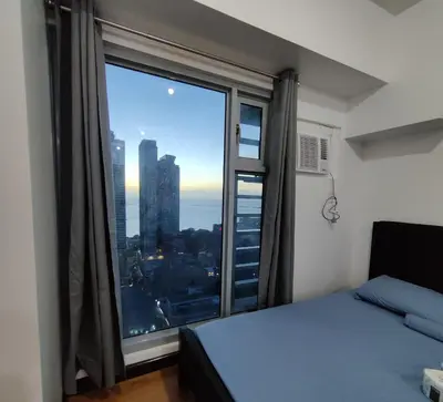 a bedroom with a large window with a view of the city at 8Adriatico Condo near US Embassy in Manila
