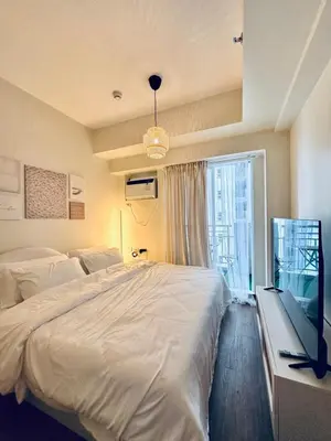 a bedroom with a large white bed and a window at The K-Butter Lounge by Kozy Mood near BGC in Manila