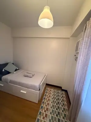 a small bedroom with a bed and a lamp at Stylish Cozy Nordic 2BR Netflix & Free Parking in Manila