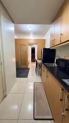 a kitchen with wooden cabinets and black counter tops at Classy Pool view low floor Condo near MoA in Manila
