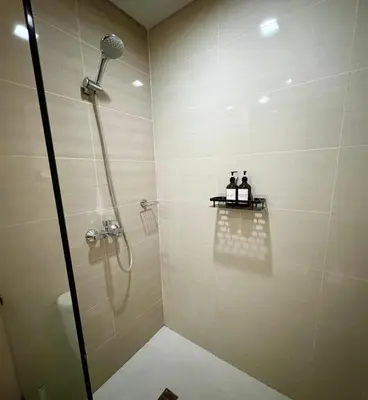 a bathroom with a shower with two people sitting on a table at Stylish 1BR Condo in 101 Newport City Near NAIA in Manila