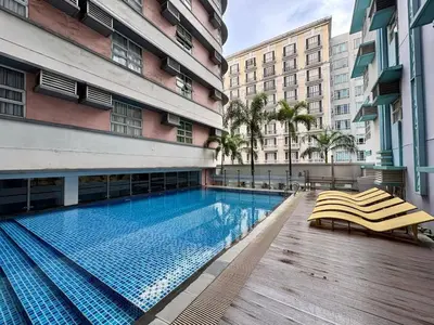 a swimming pool with two lounge chairs next to a building at Stylish 1BR Condo in 101 Newport City Near NAIA in Manila