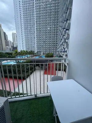 a balcony with a white table and a large building at Jazz Residences in Manila