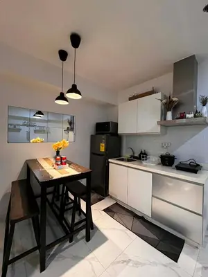 a kitchen with a table and a black refrigerator at Zyron Suite in Manila