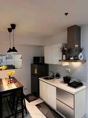 a kitchen with white cabinets and a black refrigerator at Zyron Suite in Manila