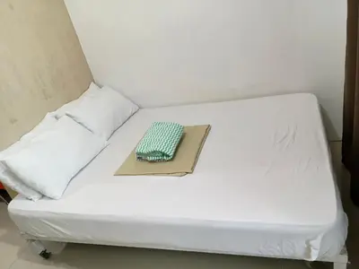 a white bed with a book on top of it at Rosaland staycation in Manila