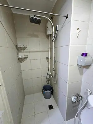 a bathroom with a shower with a bucket in it at Nest & Rest by RanDecz in Manila