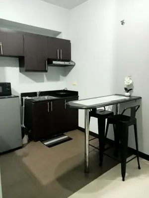 a small kitchen with a table and a sink at Stamford Executive Residences, McKinley Hill in Manila