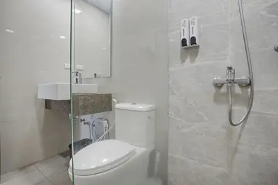 a bathroom with a toilet and a glass shower at Lovely & Spacious 2BR Home near Solaire & Okada in Manila
