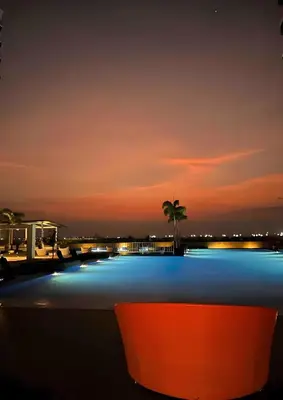 a pool at night with a palm tree in the background at 120 Sqm Modern 3Bedrooms HighRise Facing Manila Bay, Near Airports, Okada Casino, Solaire Casino, MOA with free parking in Manila