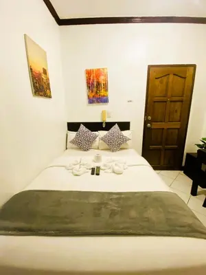 a bedroom with a white bed with a wooden door at Makati Avenue Suites in Manila