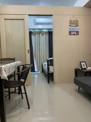 a living room with a table and chairs and a bedroom at Stern Staycation Moa in Manila